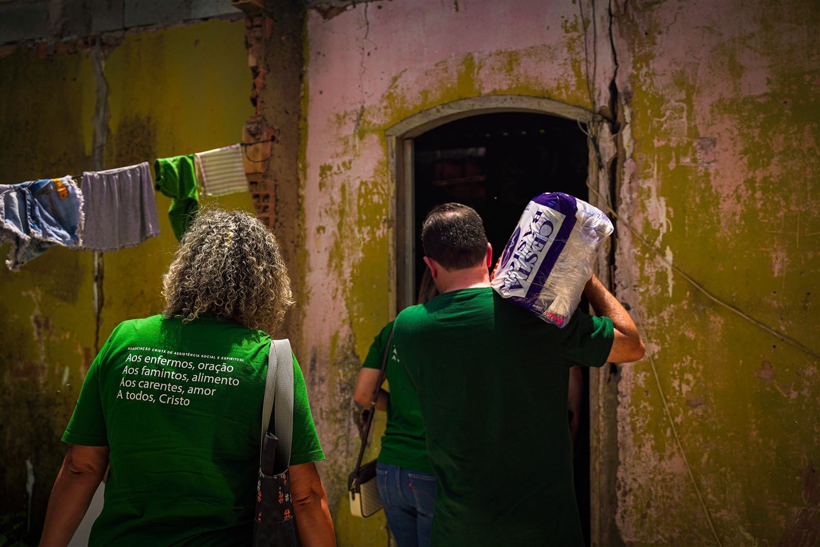 Voluntários da ACASE chegam à casa de uma família carregando uma cesta básica.