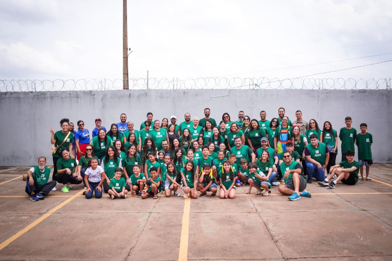 Grande grupo de voluntários e crianças com camisetas verdes da ACASE.